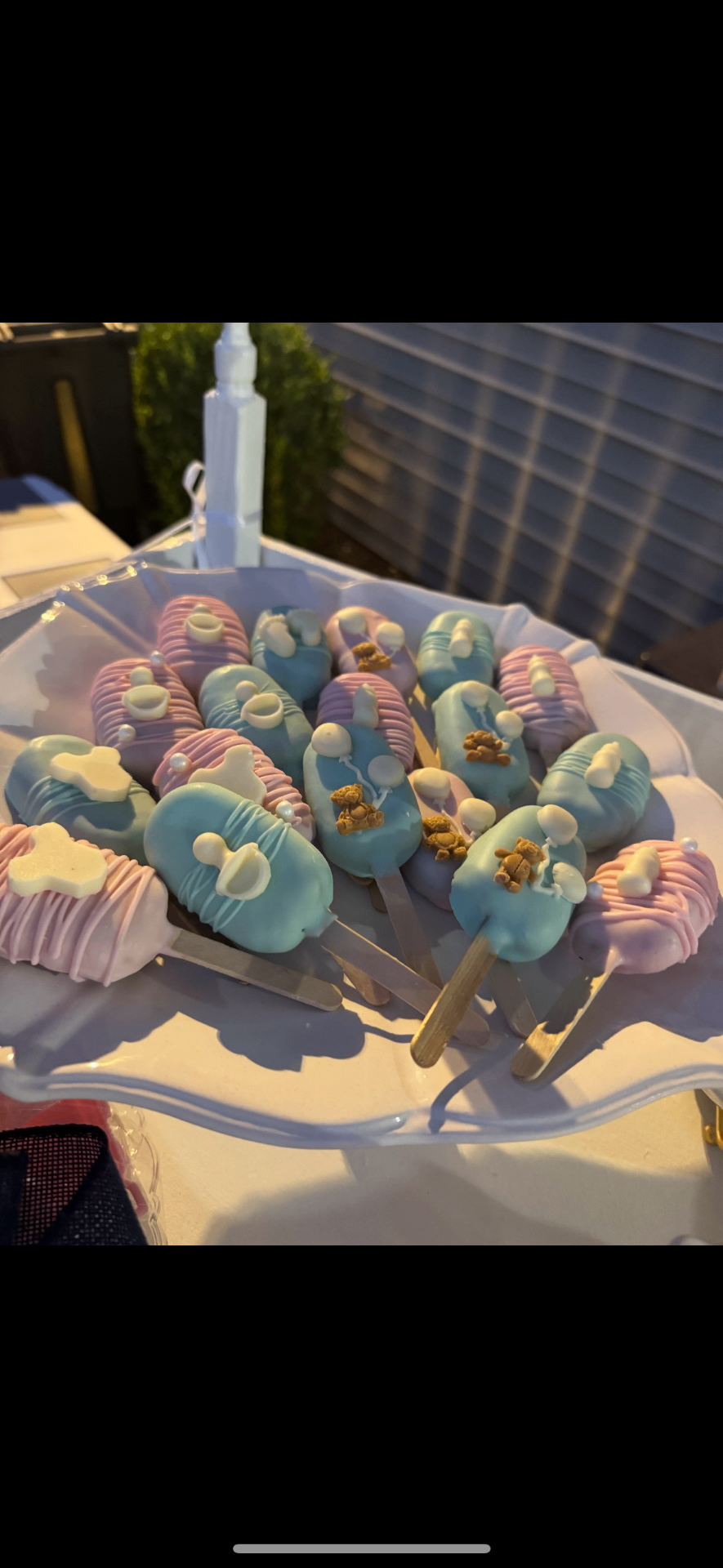 Pastel baby shower cakesicles on a scalloped plate